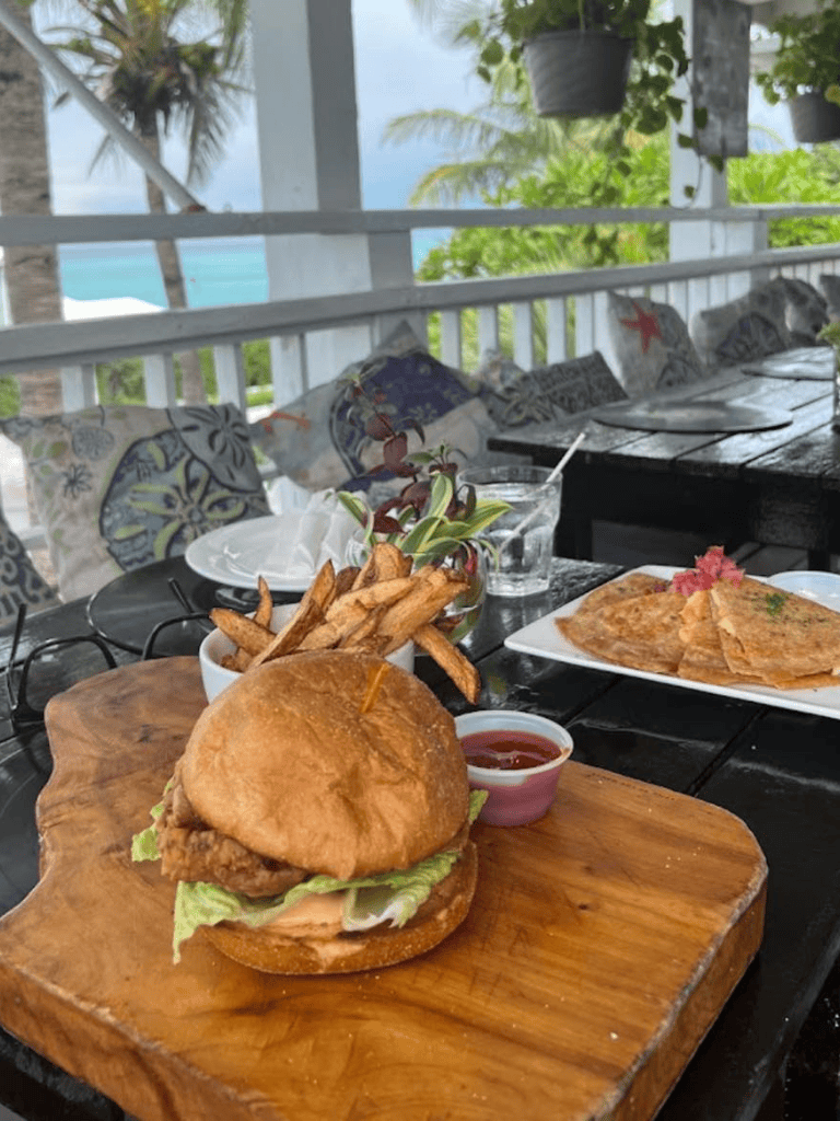 Delicious chicken sandwich with fries on a rustic wooden board at seaside restaurant.