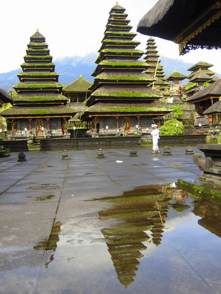Intricate Balinese Hindu Temple with Tiered Roofs and Reflection on Wet Stone Surface.