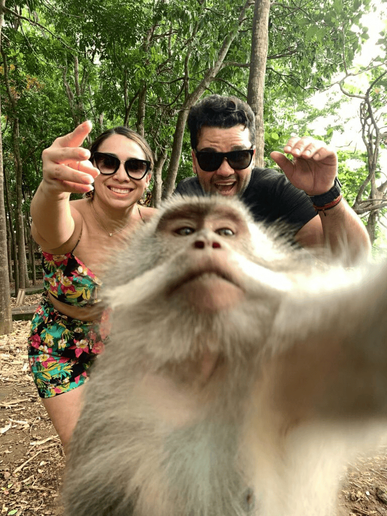 Adorable monkey selfie with happy tourists in lush forest setting.