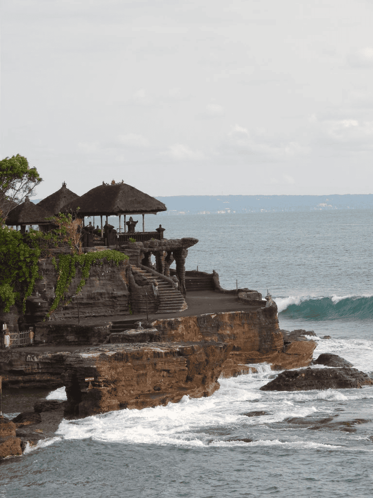 Cliffside beachfront with traditional Balinese-style structures overlooking the ocean.