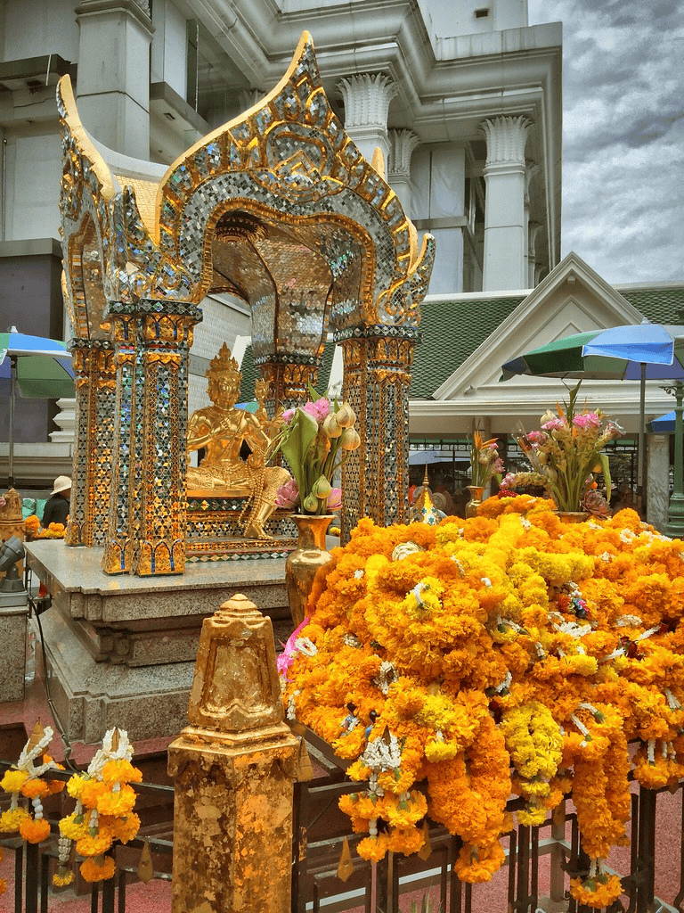 Intricate golden shrine with vibrant marigold flowers at a Thai temple.