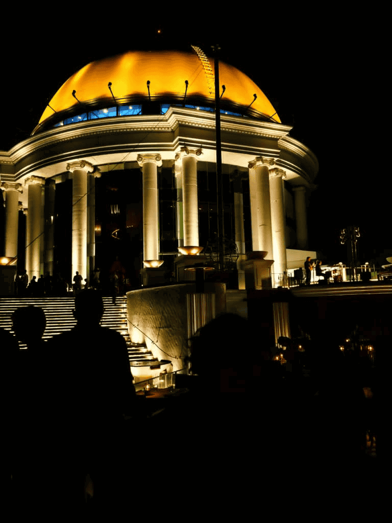 Elegant casino resort building illuminated at night with bright golden dome and classical columns, perfect for travel and entertainment.