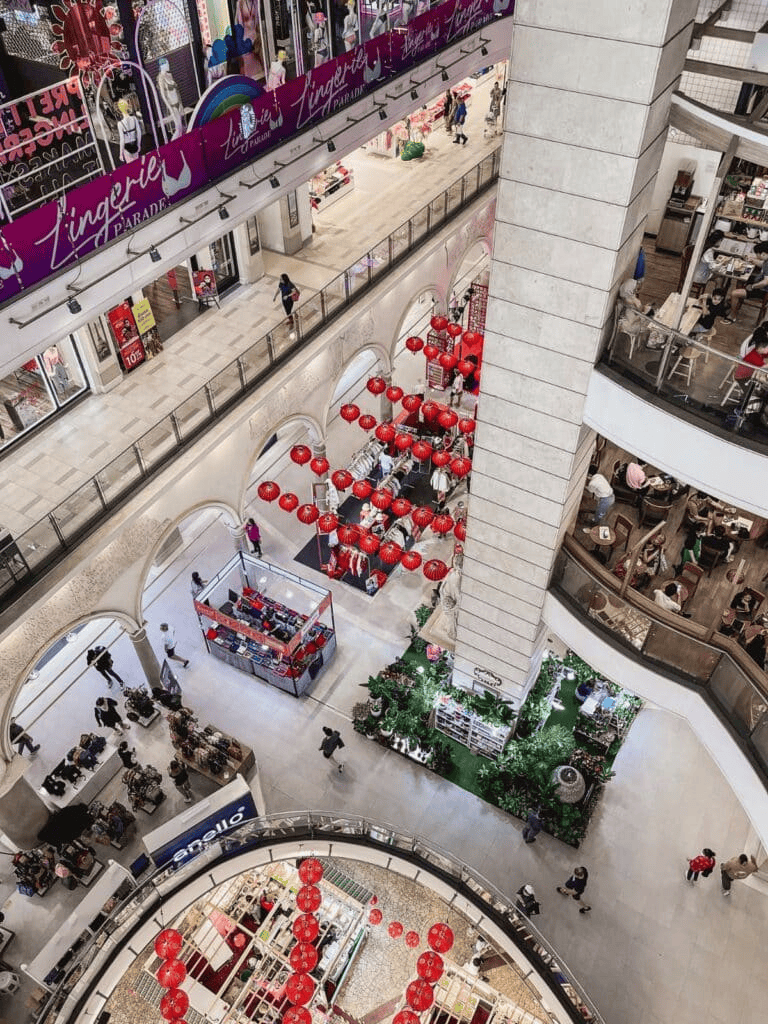 Colorful shopping mall interior with festive red lanterns and multiple retail stores.