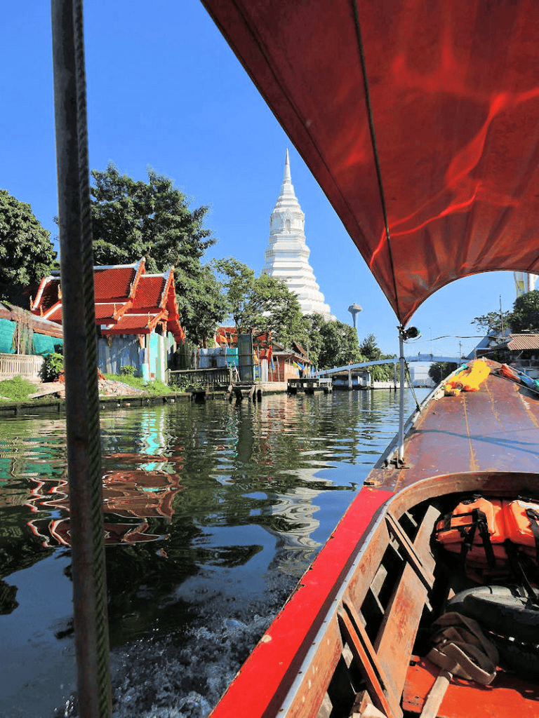 Colorful boat ride along Bangkok canal with view of Wat Arun in Thailand.