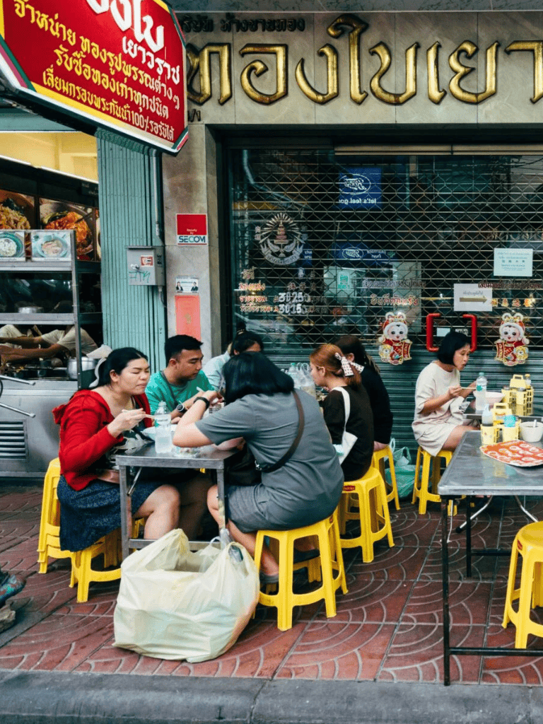 Chinatown street food market with outdoor seating and local diners, vibrant urban dining scene in Bangkok.