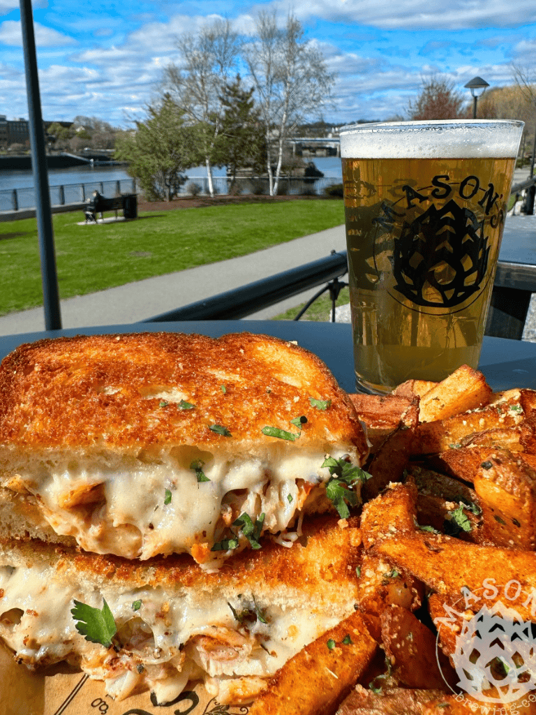 Cozy outdoor dining with gourmet grilled cheese, fries, and a craft beer by the river.