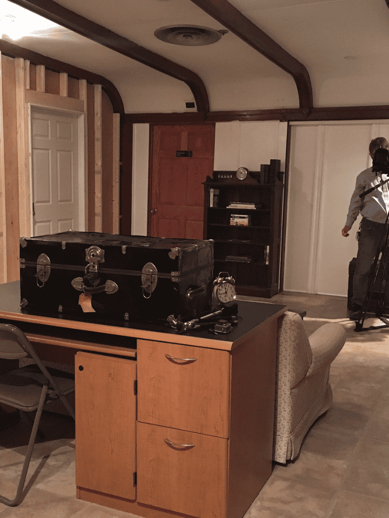 Alarm clock and suitcase on office desk in a study or creative workspace.