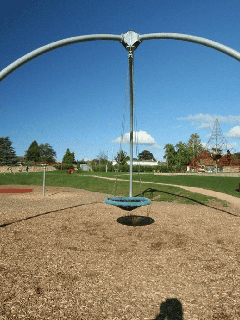 Colorful playground swing set at a local park with clear blue sky.