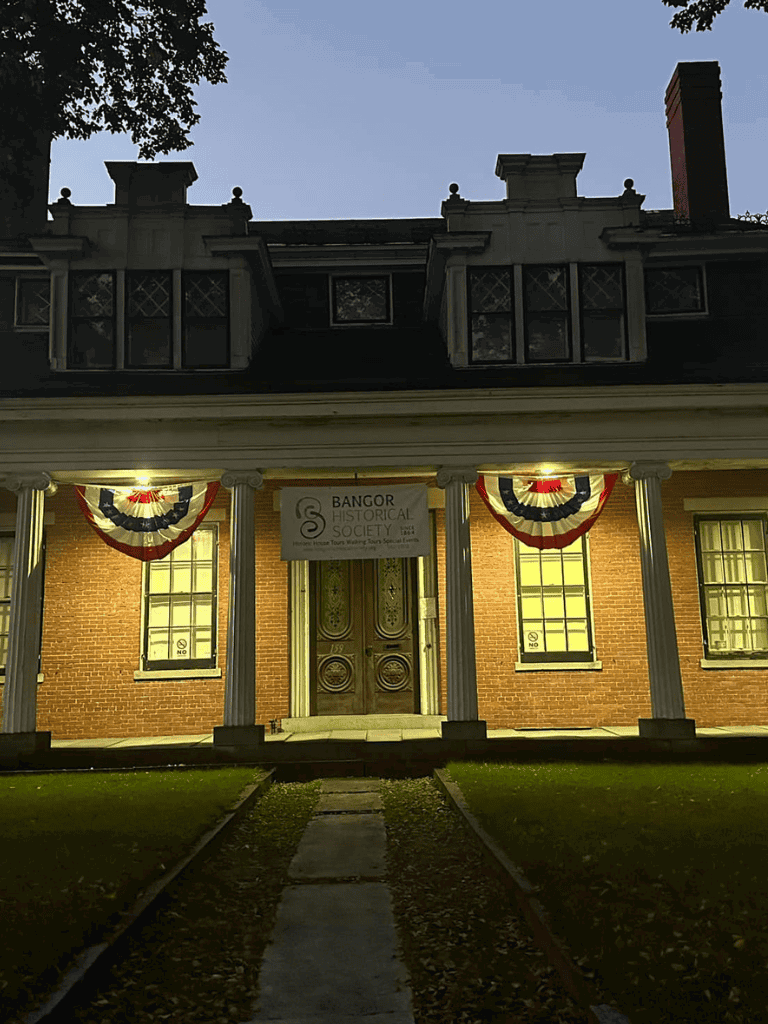 Historic Bangor Society building in Bangor, Maine, featuring colonial architecture and festive patriotic decorations.