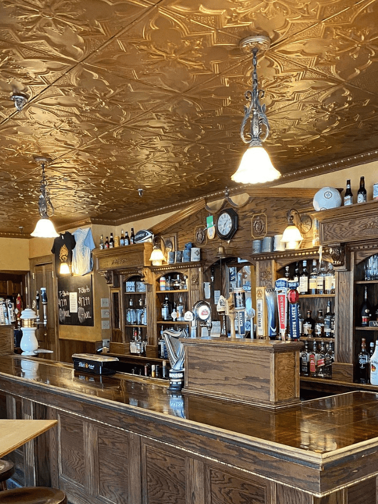 Warm wooden pub interior with brass ceiling and cozy lighting, perfect for a relaxing drink.