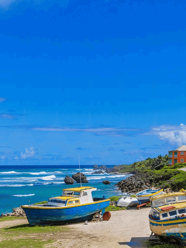 Boat on rocky coast under blue sky with ocean waves.