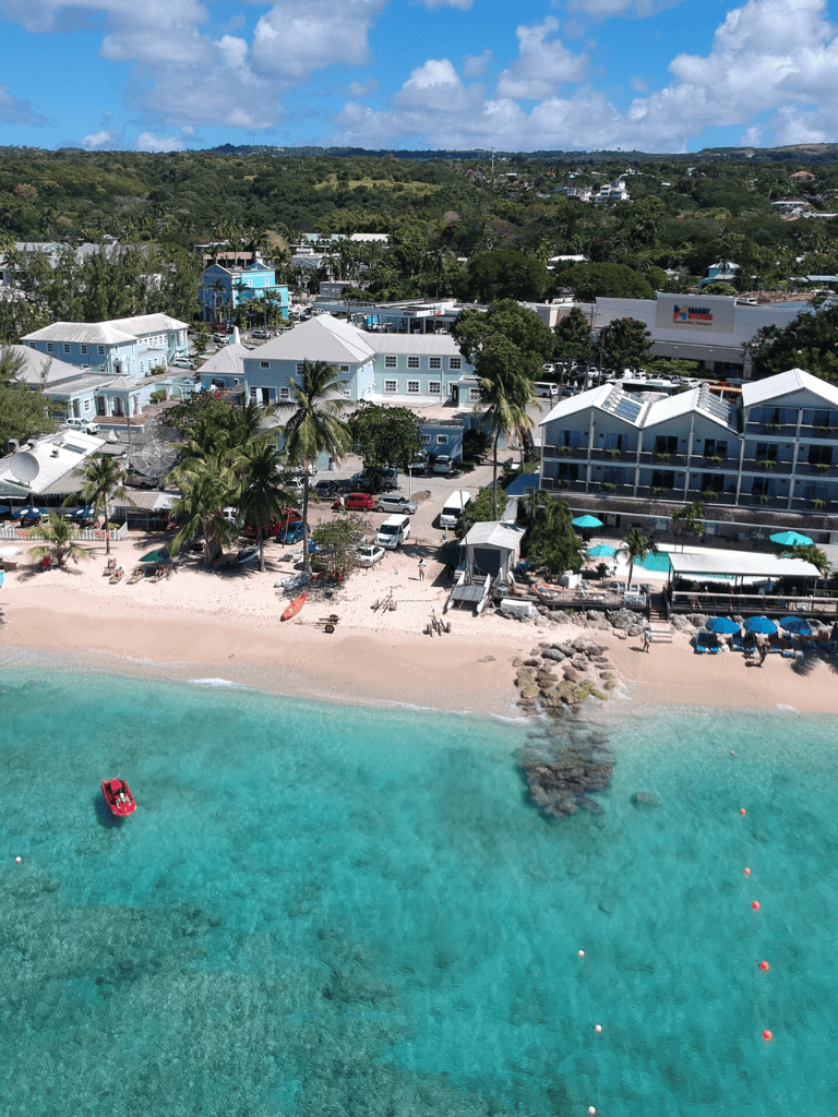 Colorful beach town with white buildings, palm trees, and clear turquoise waters.
