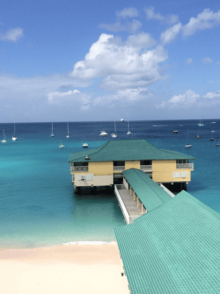 Overwater Beach Resort with turquoise waters and sailboats, perfect for tropical vacations and water activities.