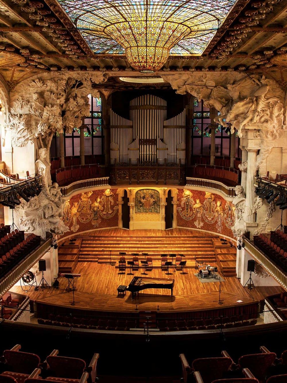 Intricate concert hall interior with ornate sculptures and a grand stained glass ceiling for musical events.