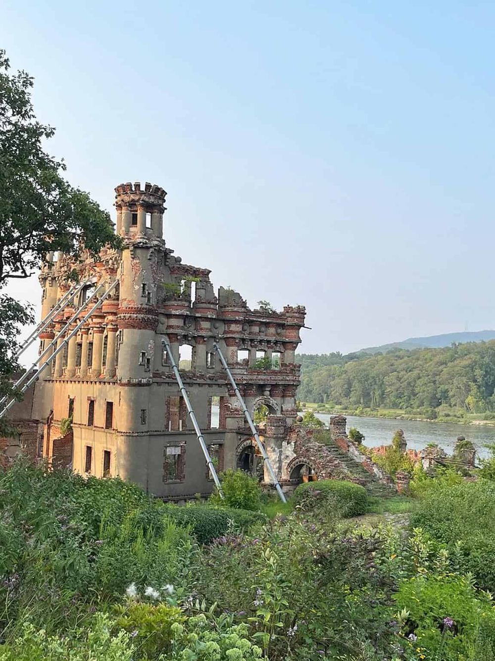 Ruined castle by the river, surrounded by lush greenery and scenic landscape, historic site, travel destination, QuestForDirections.