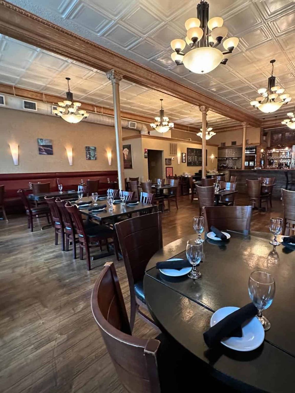 Elegant restaurant interior with wooden tables, chairs, and stylish lighting, perfect for dining and gatherings.