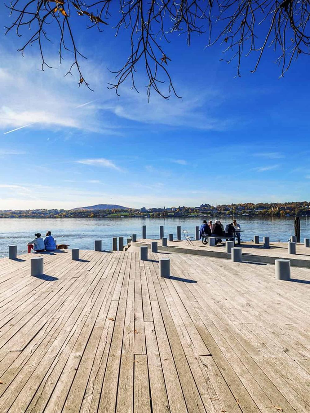 Relaxing riverside dock scene with visitors enjoying scenic views on sunny day.