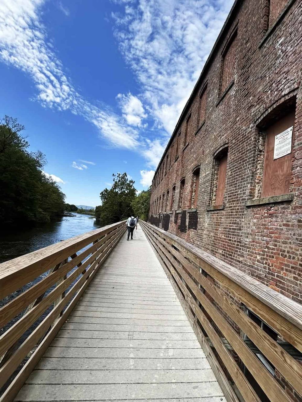 Riverwalk trail along historic brick building in Quest for Directions location, scenic outdoor urban path.