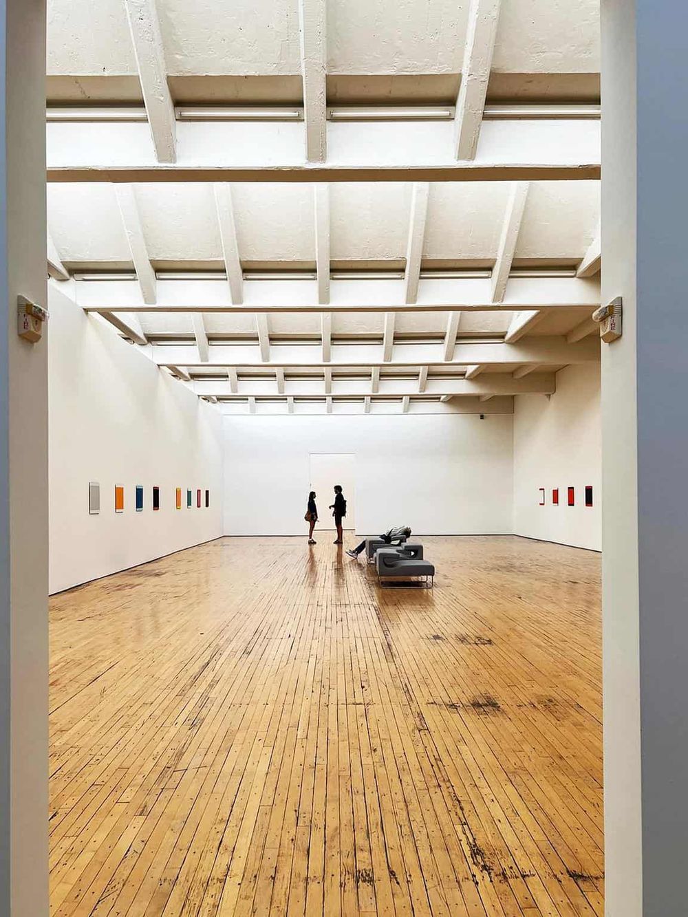 Bright modern art gallery interior with minimalist design and colorful artwork on white walls.
