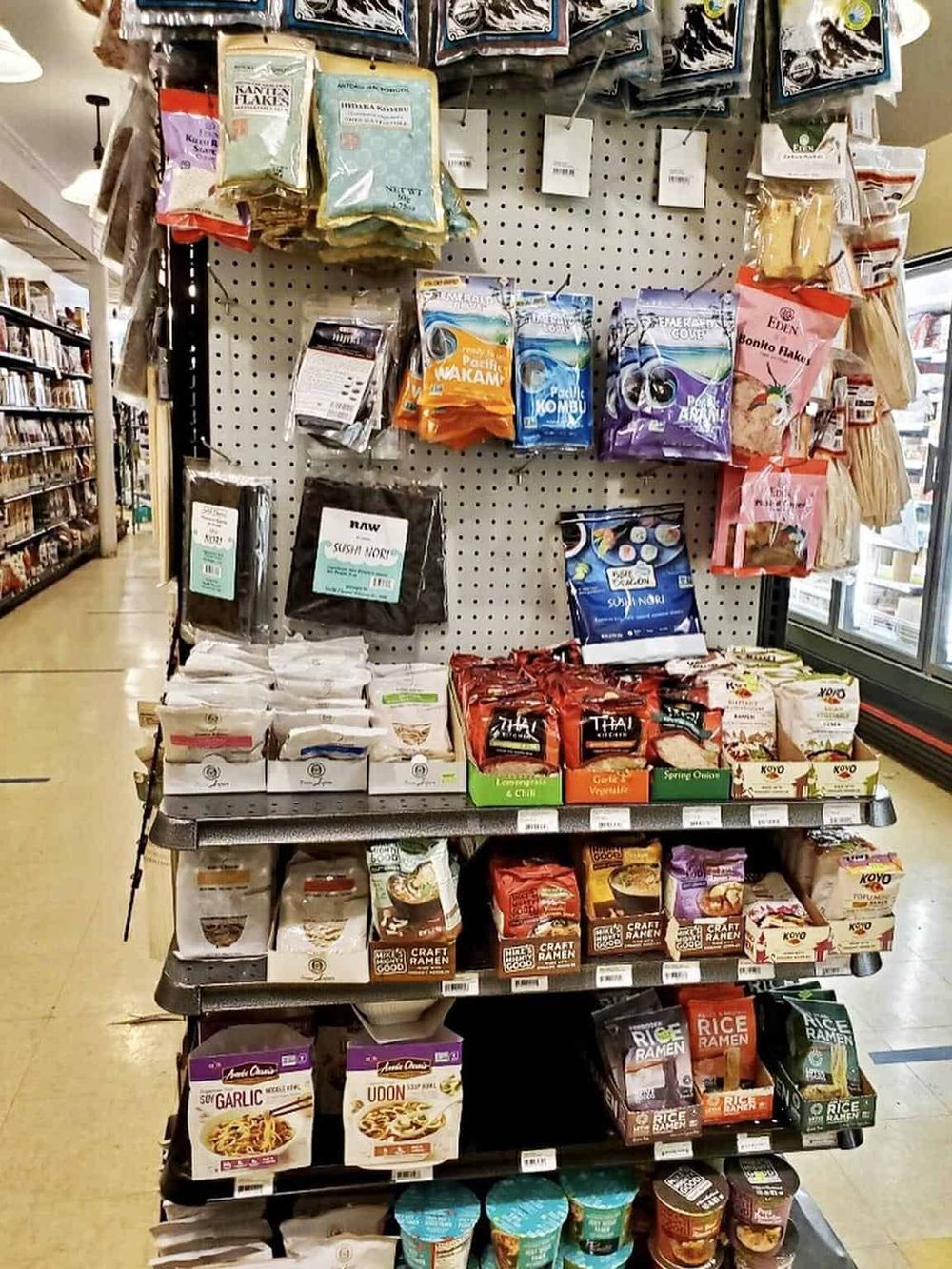 Assorted Asian noodles and rice packages in a grocery store aisle for authentic cooking ingredients.