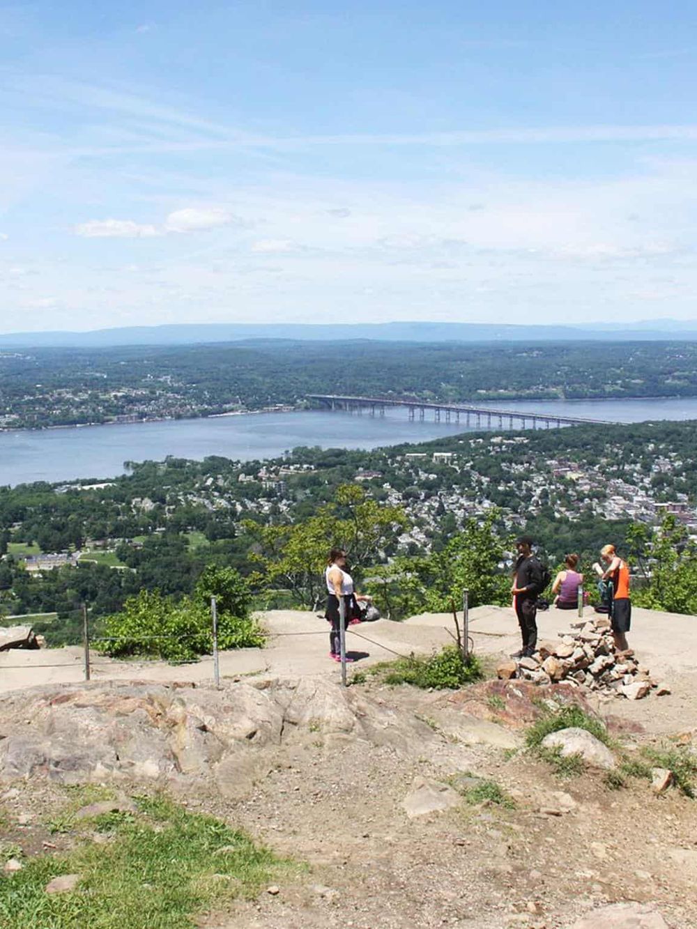 Breathtaking view from a hiking trail overlooking a city, river, and mountains, perfect for adventure seekers.