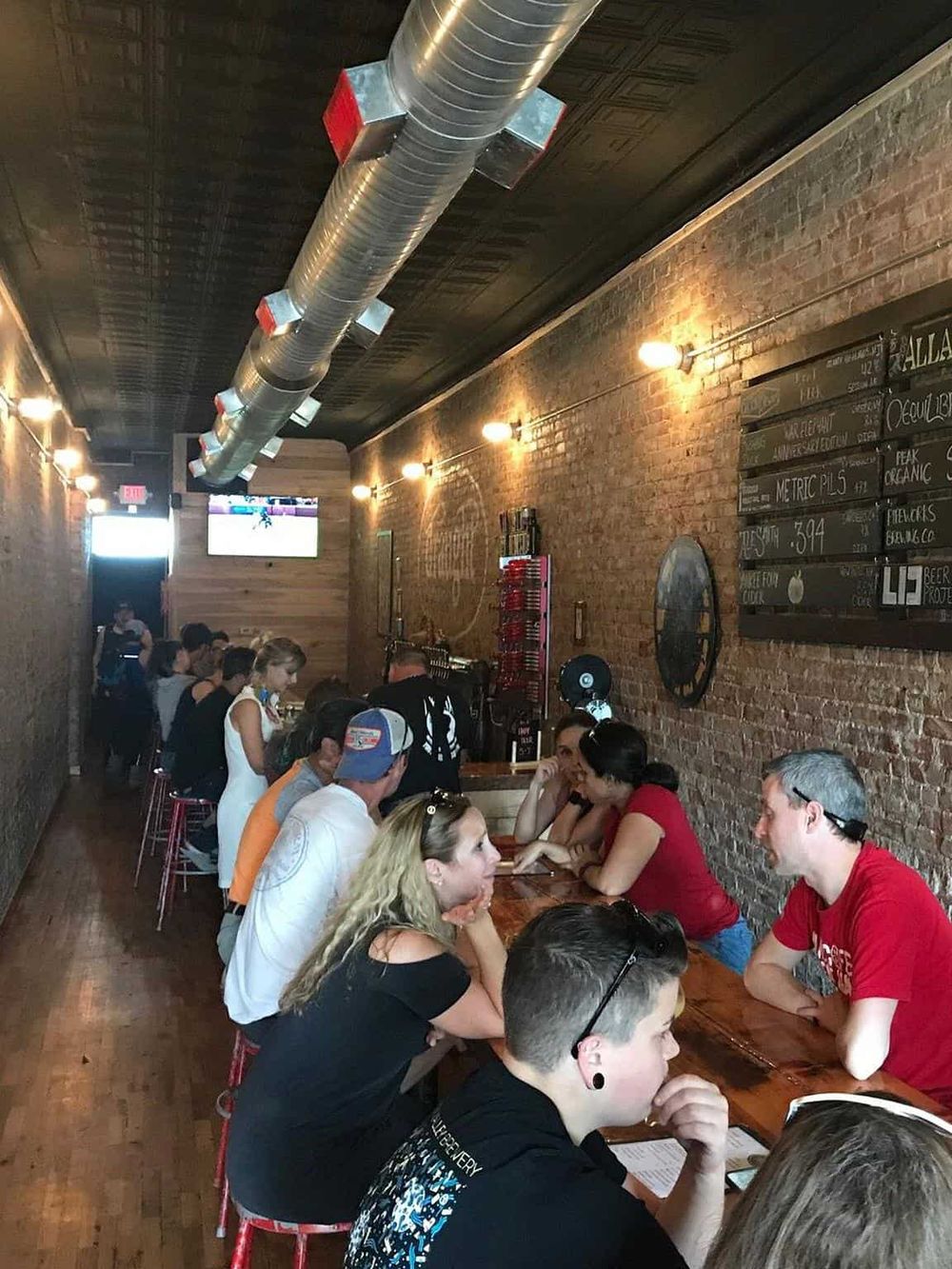 Bright bar interior at QuestForDirections brewery with patrons enjoying drinks and socializing.