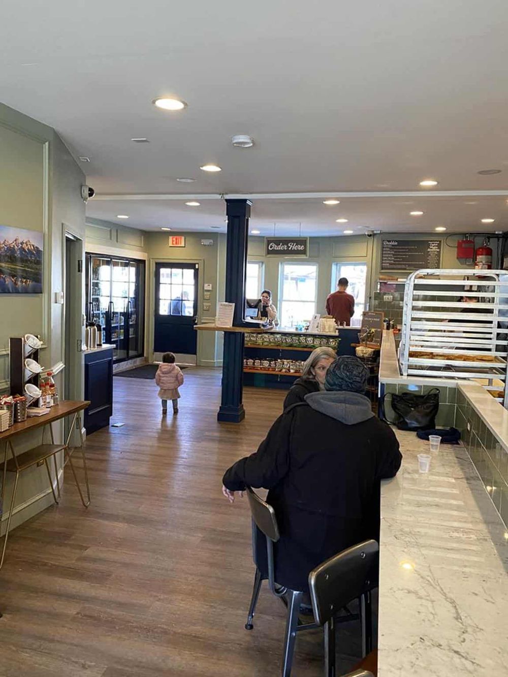 Bright interior of a cozy cafe with customers ordering and enjoying food and drinks.
