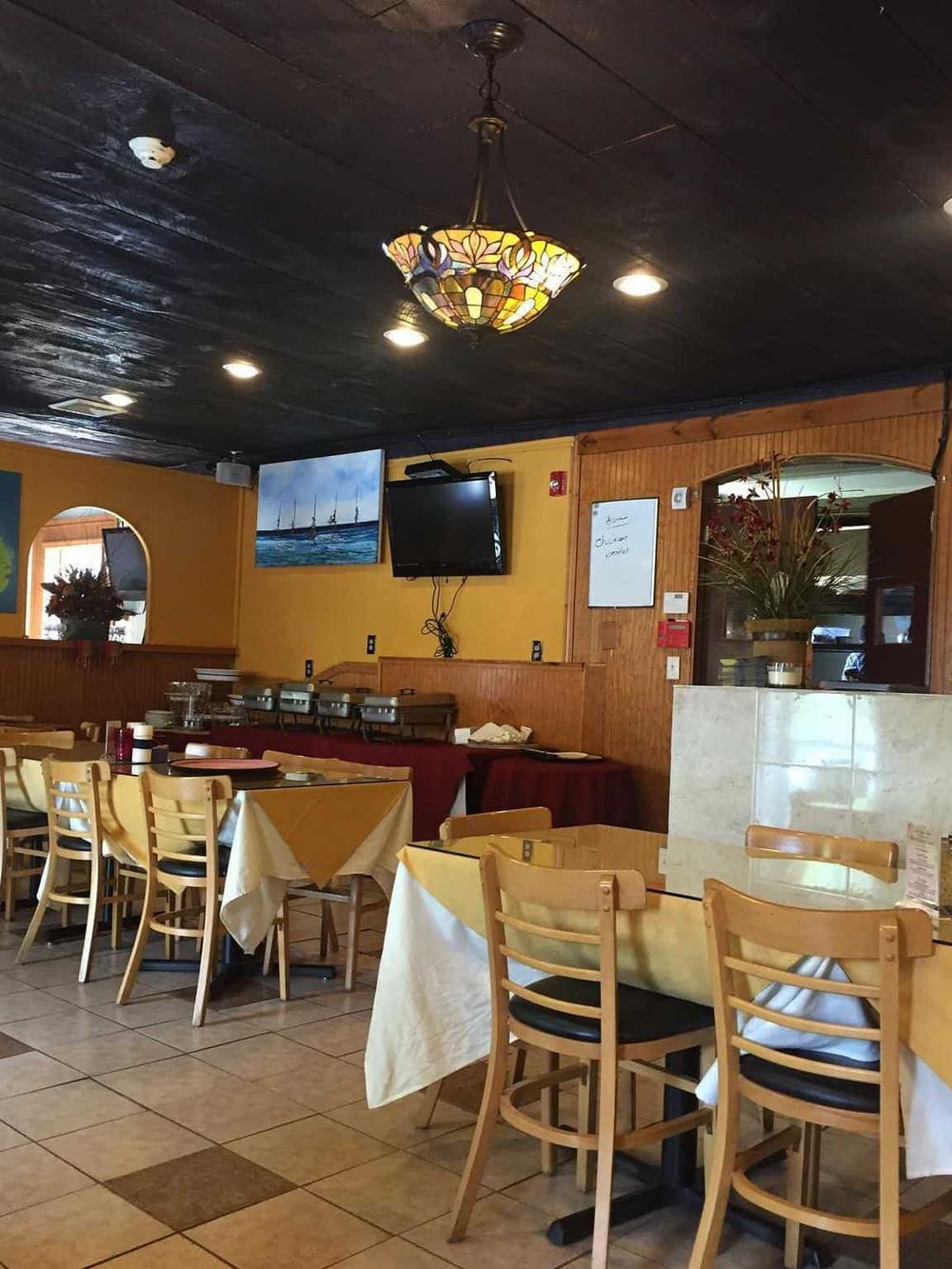 Cozy restaurant interior with wooden furniture, yellow walls, and a decorative ceiling lamp.