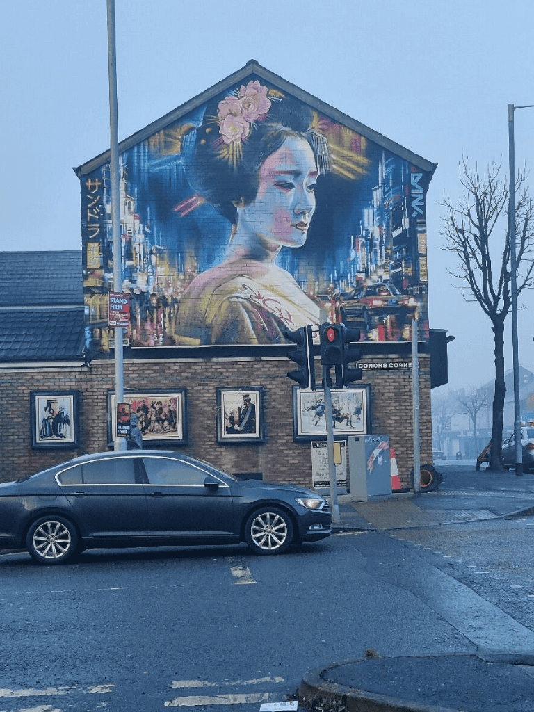 Colorful mural of Geisha artwork in a city street scene, highlighting urban art and cultural expression.
