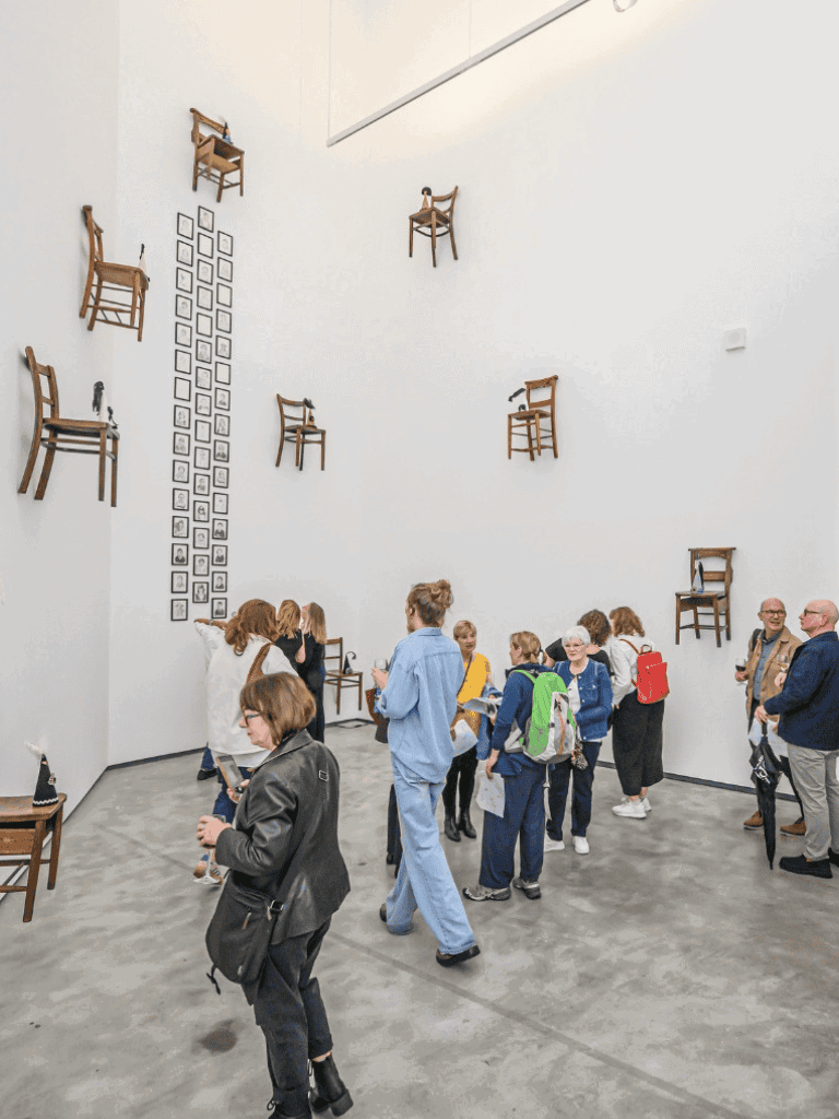 Chairs mounted on white gallery walls in an art exhibit.