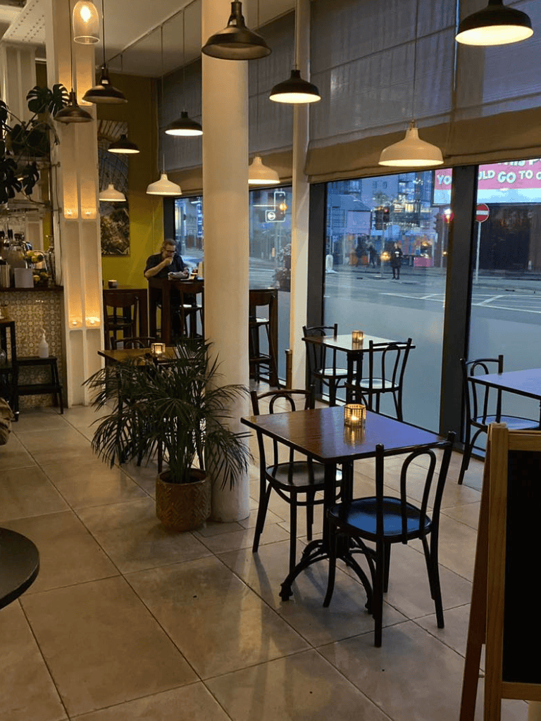 Cozy modern café interior with large windows, decorative lighting, and inviting seating area.
