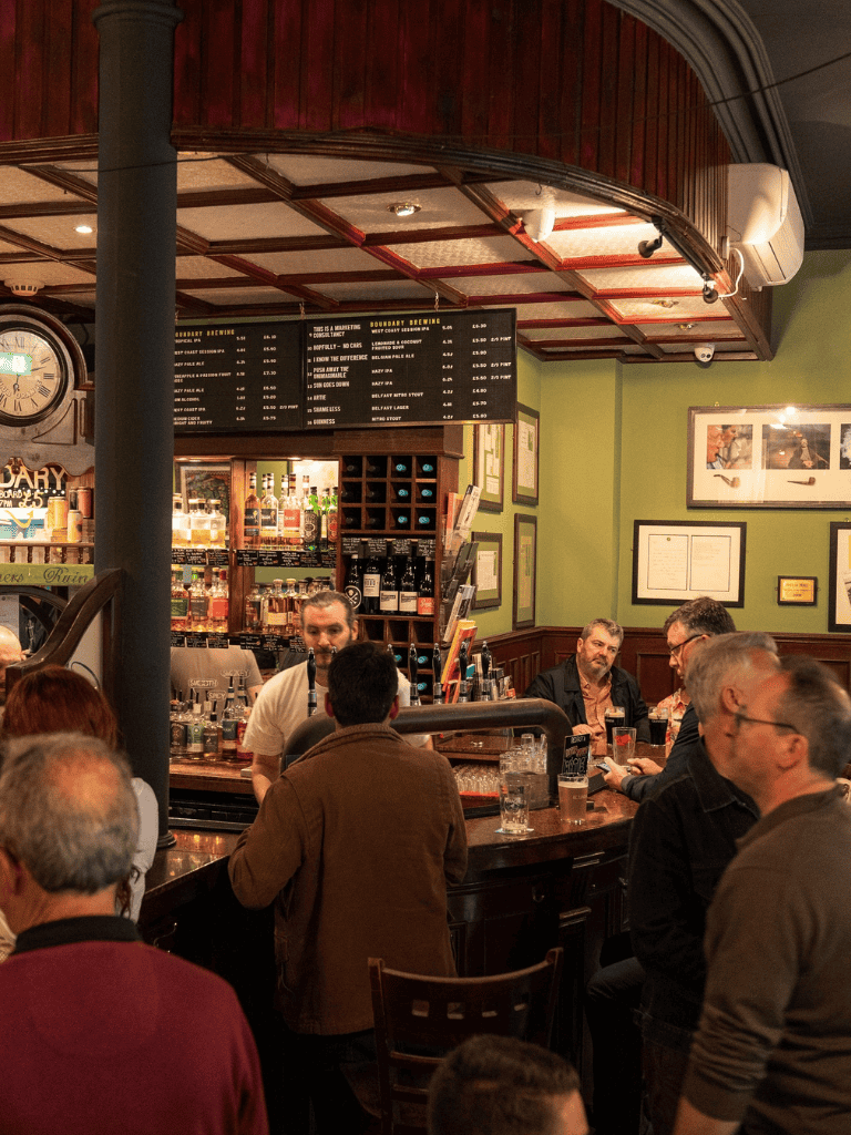 Craft beer pub with customers enjoying drinks at the bar in a cozy, welcoming atmosphere.