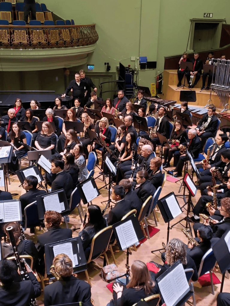 Orchestra performing at a concert hall with musicians reading sheet music and conducting.
