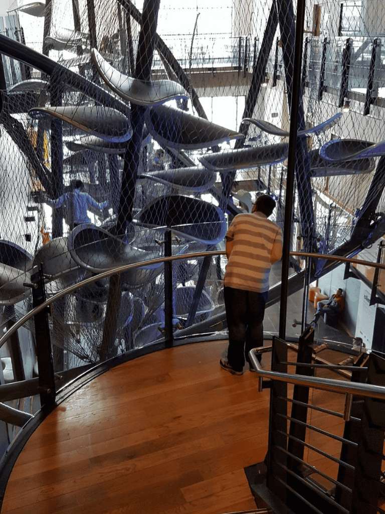 Unusual art installation with colorful chairs, onlookers, modern interior, QuestForDirections museum exhibit.