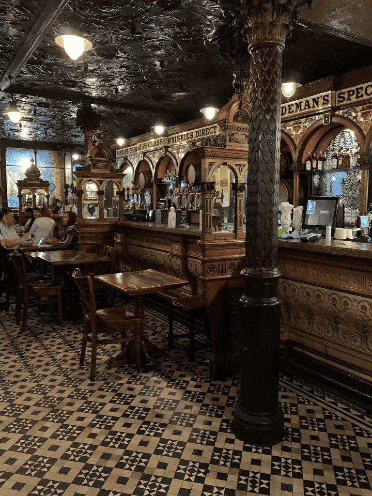 Charming vintage pub interior with ornate woodwork and patterned tiles, ideal for a cozy dining experience.