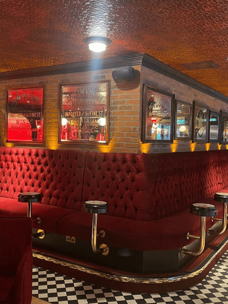 Luxurious bar with red tufted seating, brick walls, and vintage decor at QuestForDirections.