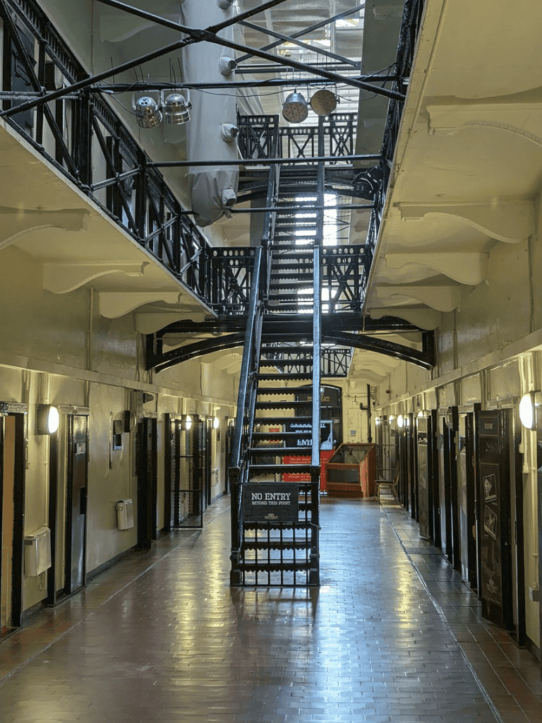 Staircase inside historic building, black metal structure, vintage industrial style, bright natural light.