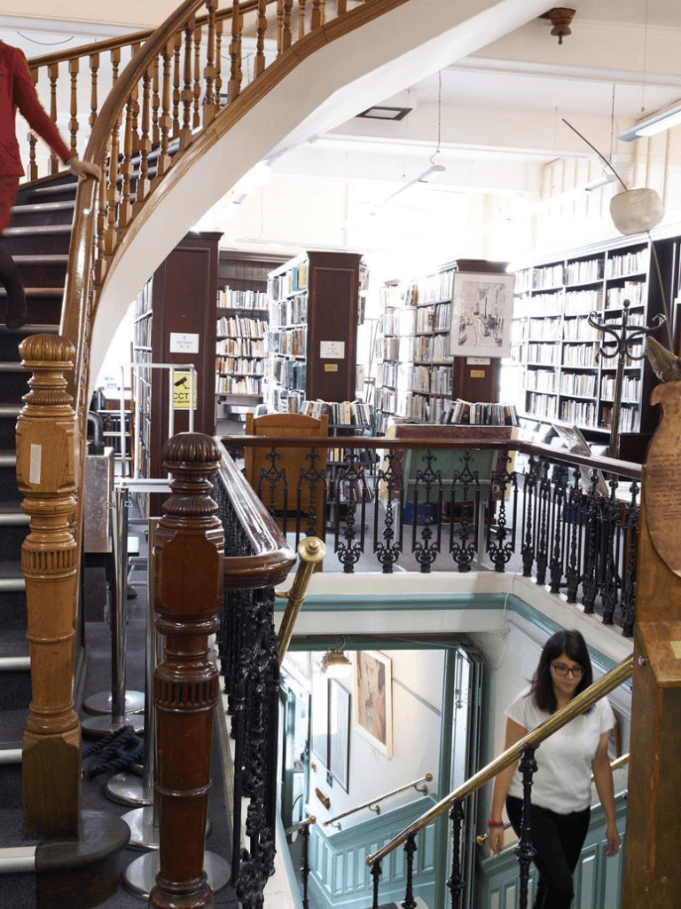 Staircase inside cozy library featuring wooden handrails and bookshelves filled with books.