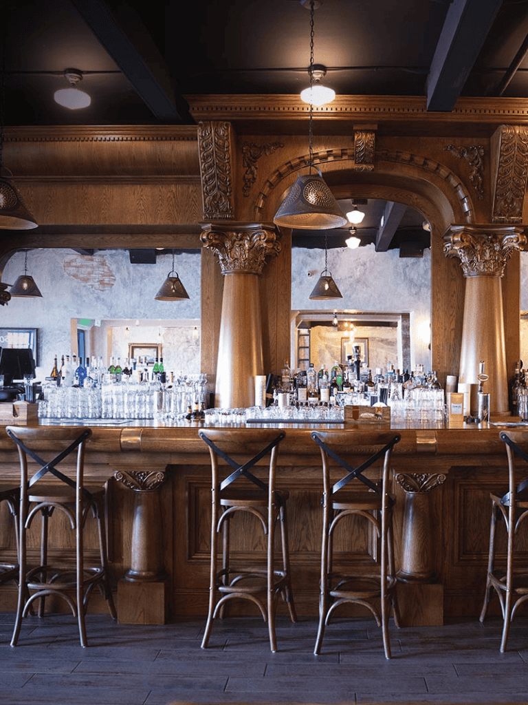 Luxury wooden bar interior with ornate columns and ambient lighting.