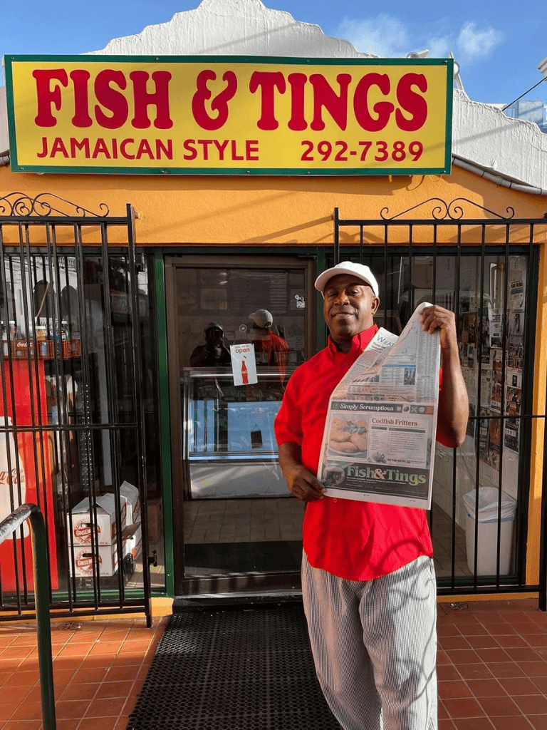 Fish and Tings Jamaican Style restaurant exterior with a man holding a newspaper, vibrant Caribbean cuisine, welcoming atmosphere.