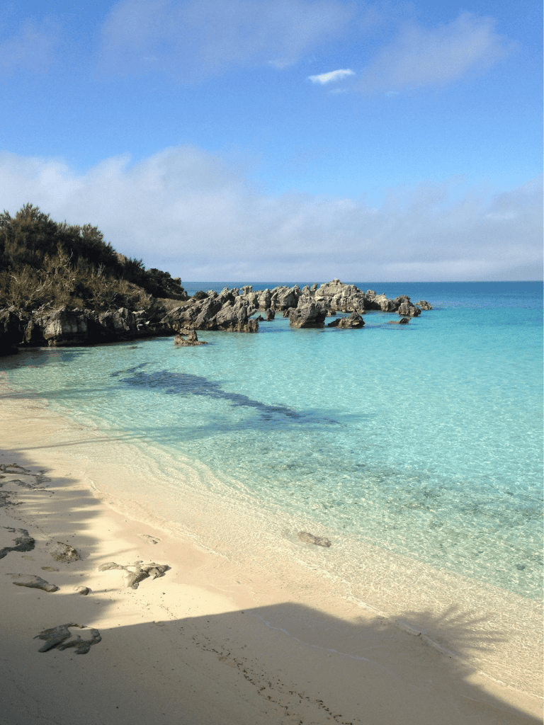 Tranquil beach with clear turquoise waters and rocky shoreline, perfect for travel and adventure.