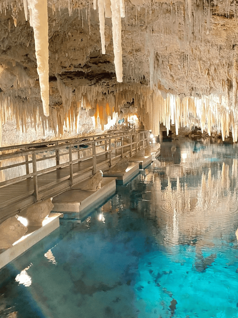 Stunning underground cave with stalactites and crystal-clear water, perfect for adventure tourism.