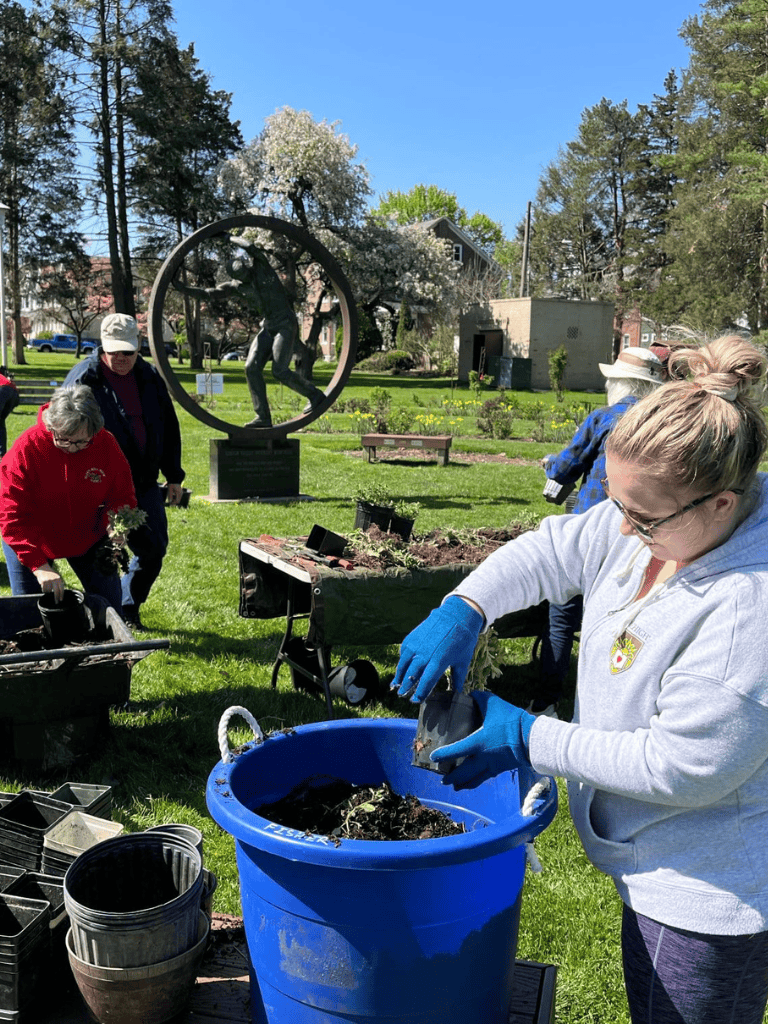 Kids gardening and planting flowers at outdoor community event for environmental awareness and education.