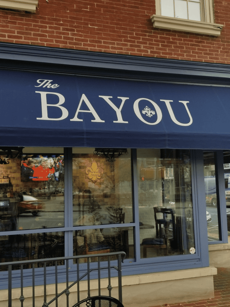 Elegant restaurant storefront with "The Bayou" sign and blue awning, welcoming diners with cozy ambiance.
