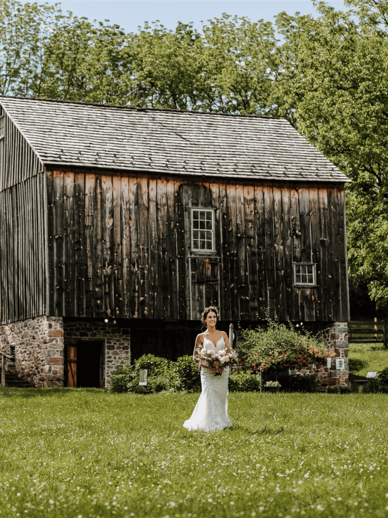 Rustic barn wedding photography with bride in white wedding dress and floral bouquet.