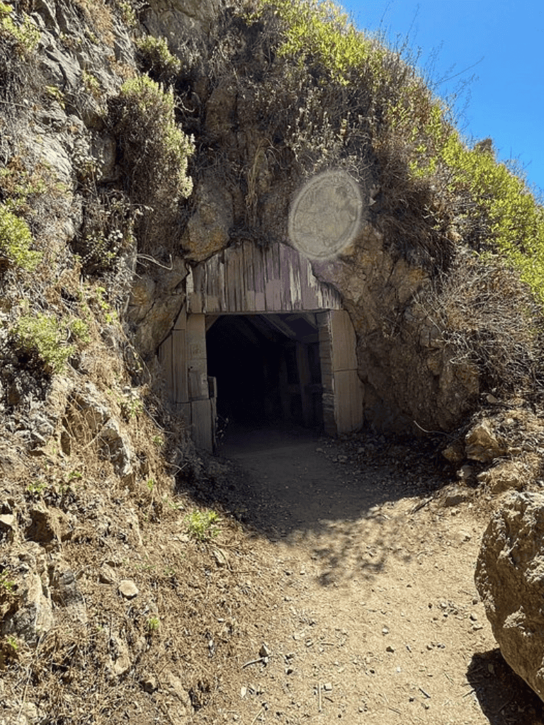 Hidden tunnel entrance in rocky hillside for outdoor adventures and exploration.