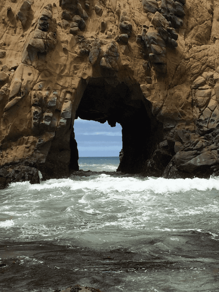 Vast ocean view through rocky sea cave at the coast.