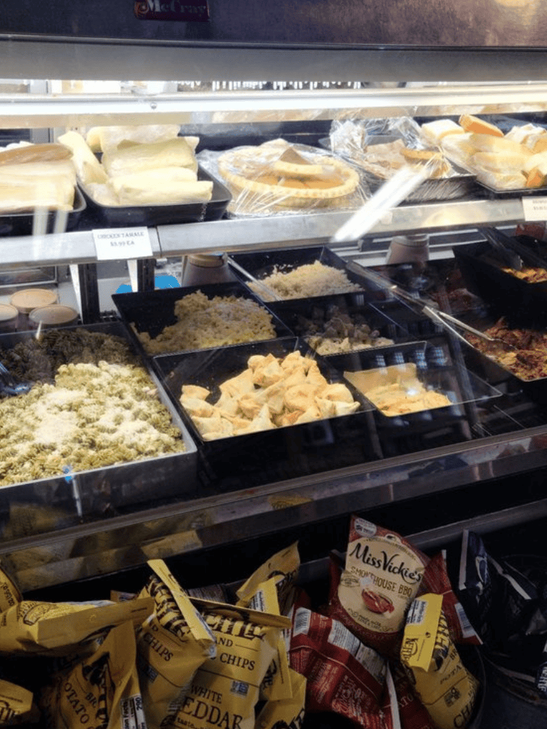 Cheese and deli counter at a grocery store with various cheese and prepared foods.