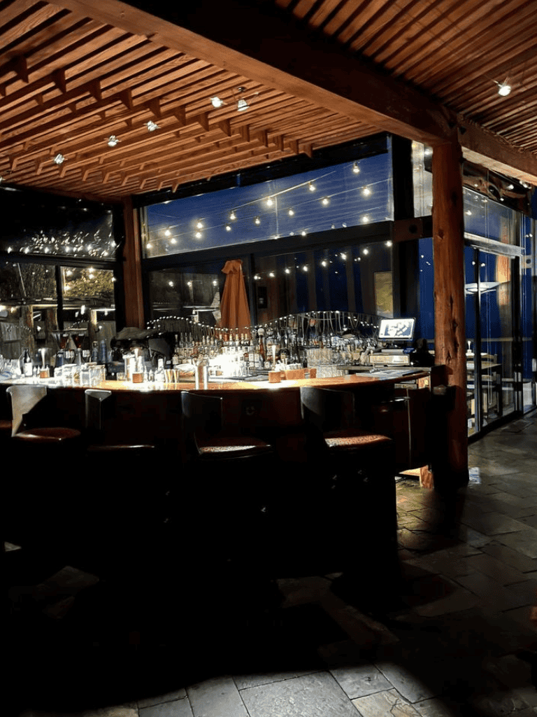 Cozy upscale bar with warm wooden decor, string lights, and a modern ambiance for social gatherings.