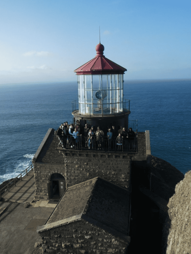 Guided lighthouse tour at Cape Reinga, New Zealand with ocean views and visitors enjoying the scenic spot.